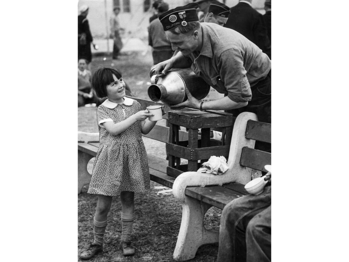 March 13, 1933: Barbara Jean McMannis gets a cup of milk from an American Legion volunteer at City Hall Square in Compton, following the Long Beach earthquake.