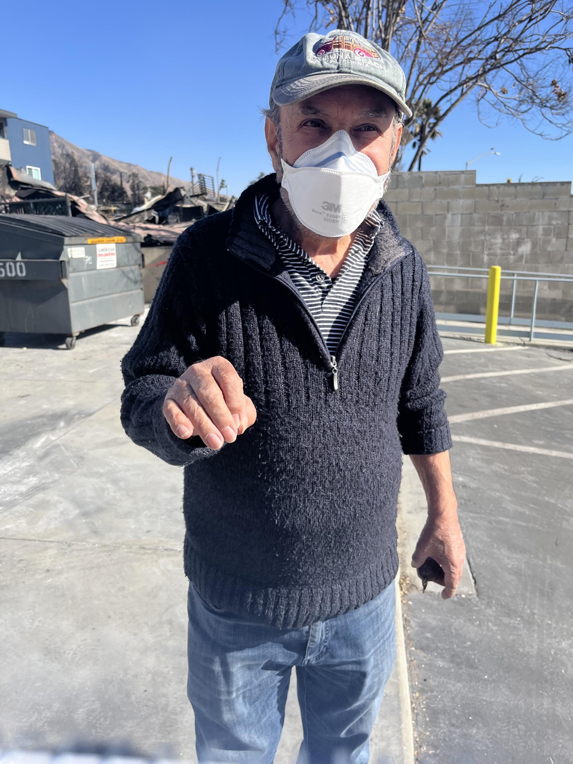 Shawn Shakhmalian, owner of Nancy's Greek Cafe, stands in the parking lot of his restaurant wearing a hat and an N95 mask.
