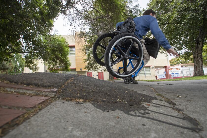 LOS ANGELES, CALIF. -- THURSDAY, SEPTEMBER 26, 2019: David Radcliff, who has cerebral palsy, tumbles over a section of broken sidewalk on Jefferson Blvd. across from the USC campus in Los Angeles, Calif., on Sept. 26, 2019. (Brian van der Brug / Los Angeles Times)