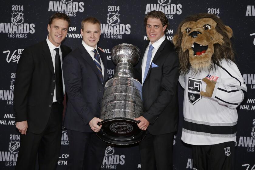 Kings executive Luc Robitaille, left, and players Dustin Brown and Anze Kopitar pose with the Stanley Cup on June 24.
