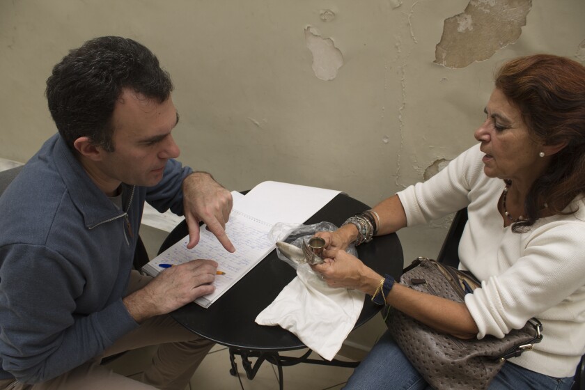 Vicky Khatchadurian shows Vahé Tachjian silver utensils and a small cup