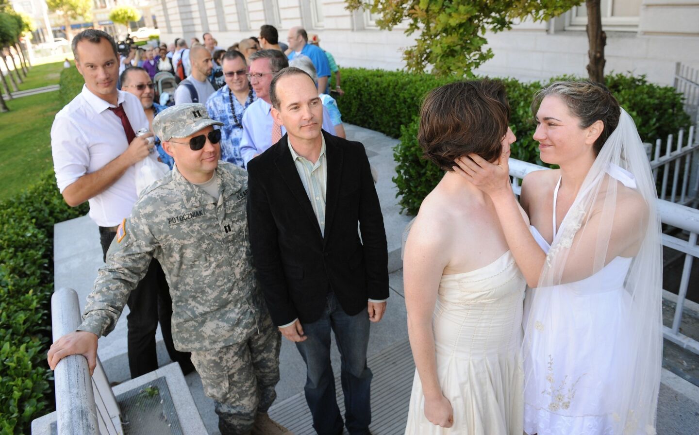 Elizabeth Carey, left, and Cyntia Wides embrace as Army Sgt. Michael Potoczniak and his partner Todd Saunders wait patiently in line to get married at City Hall in San Francisco on Saturday.