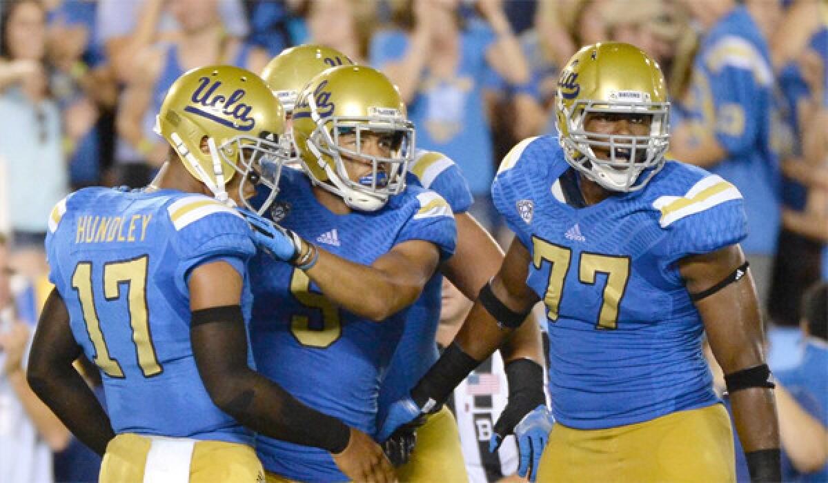 Jordan Payton, center, Brett Hundley, left, and Torian White, right, celebrate after a touchdown during UCLA's 58-20 victory over Nevada.