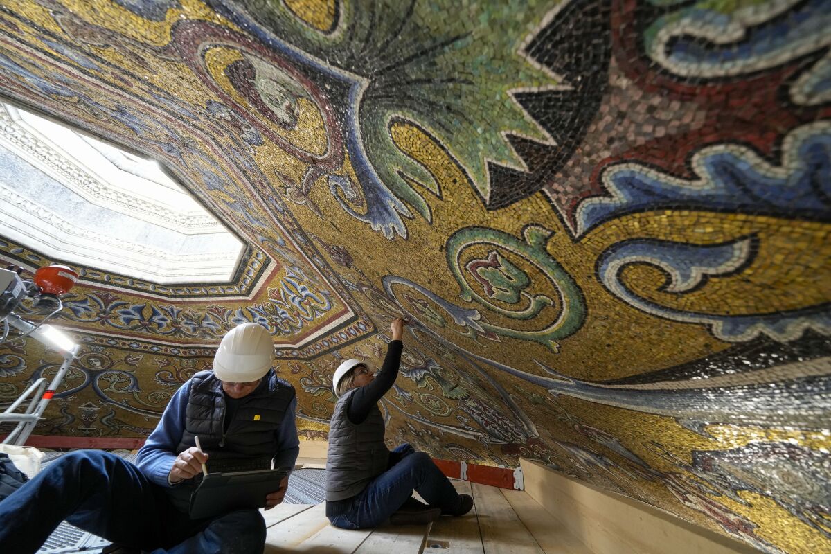 Restorers Chiara Zizola, right, and Roberto Nardi work on the restoration of the mosaics that adorn the dome of one of the oldest churches in Florence, St. John's Baptistery, in Florence, central Italy, Tuesday Feb. 7, 2023. The restoration work will be done from an innovative scaffolding shaped like a giant mushroom that will stand for the next six years in the center of the church, and that will be open to visitors allowing them for the first and perhaps only time, to come come face to face with more than 1,000 square meters of precious mosaics covering the dome. (AP Photo/Andrew Medichini)