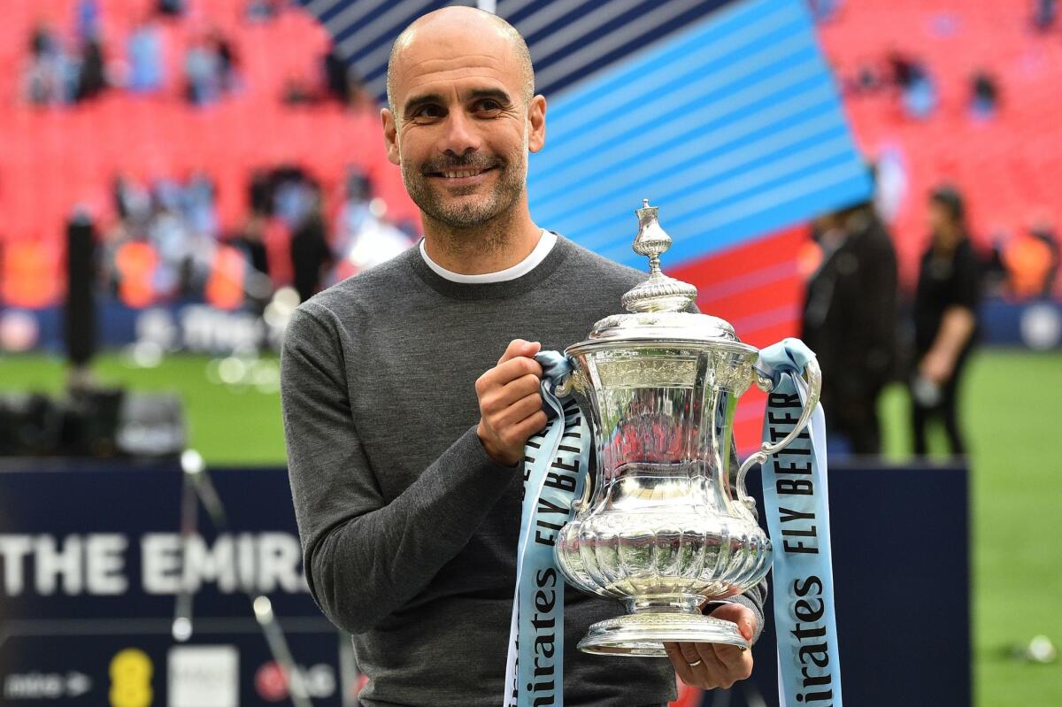 Pep Guardiola holds the winner's trophy as the players celebrate victory after the English FA Cup final in May.