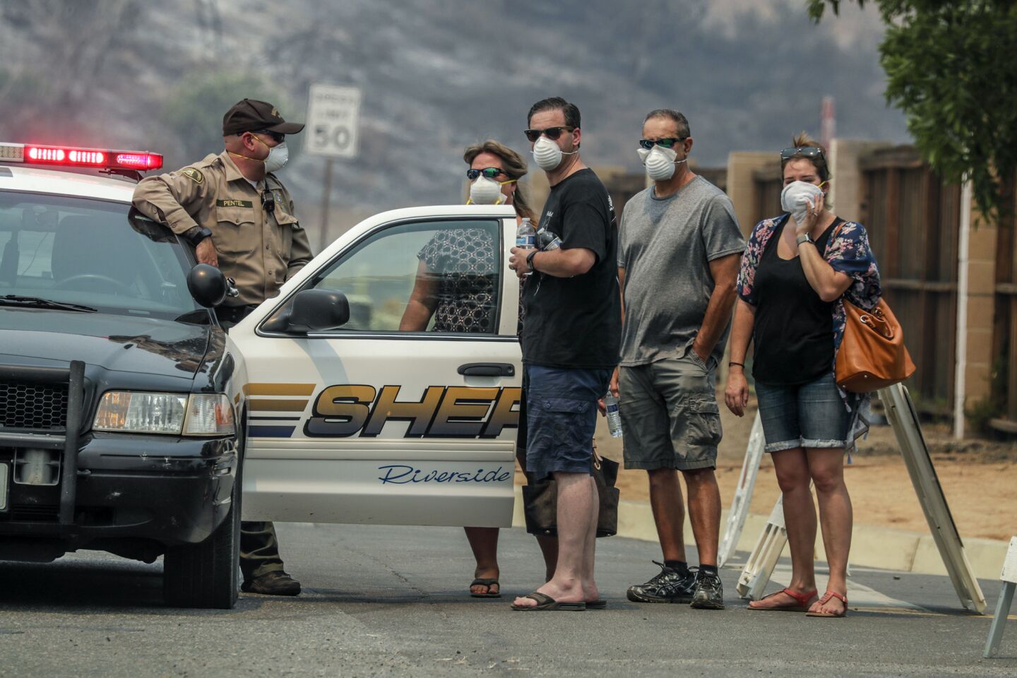 Residents and law enforcement wear breathing mask to avoid the thick smoke created by Holy Fire in Lake Elsinore.