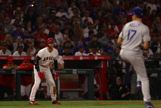 The Angels' Shohei Ohtani steps away from third base and watches Dodgers pitcher Joe Kelly deliver a throw