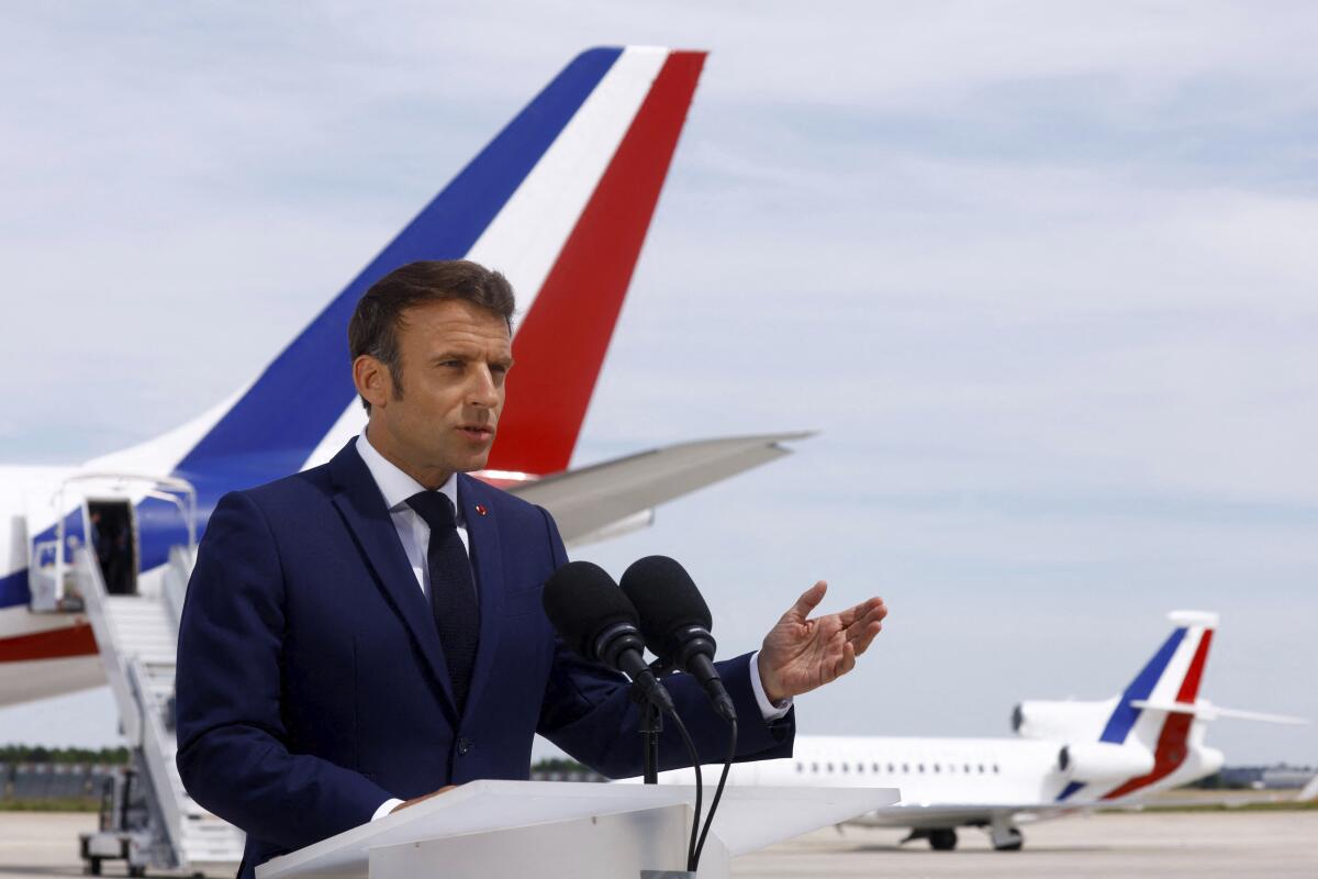 French President Emmanuel Macron delivers a statement on the tarmac in front of his presidential plane before his departure to visit French NATO troops stationed in Romania, at Paris-Orly airport in Orly, Tuesday, June 14, 2022. Emmanuel Macron urged the French to give him a "strong majority" Sunday in the second, decisive round of nationwide parliamentary elections. (Gonzalo Fuentes/Pool via AP)