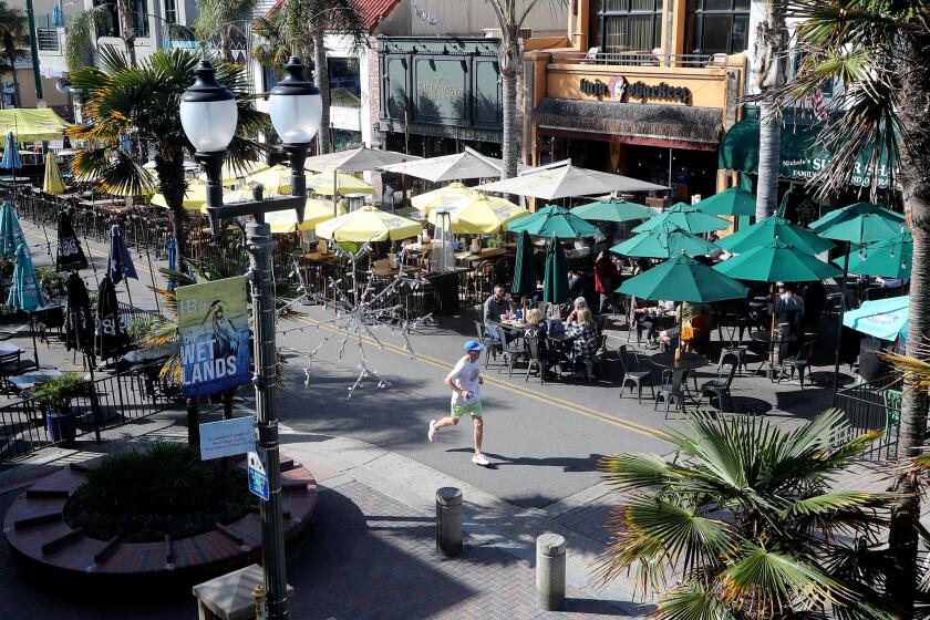 A man jogs along Main Street, between Walnut Avenue and Olive Avenue, on Wednesday afternoon in Huntington Beach. The Huntington Beach City Council on Tuesday night discussed ending the COVID-inspired outdoor dining on Main Street, and opening the second block to traffic again. (Kevin Chang / Daily Pilot)