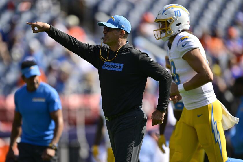  Jim Harbaugh points instructions to the Chargers as  Justin Herbert (10) jogs onto the field in Denver.