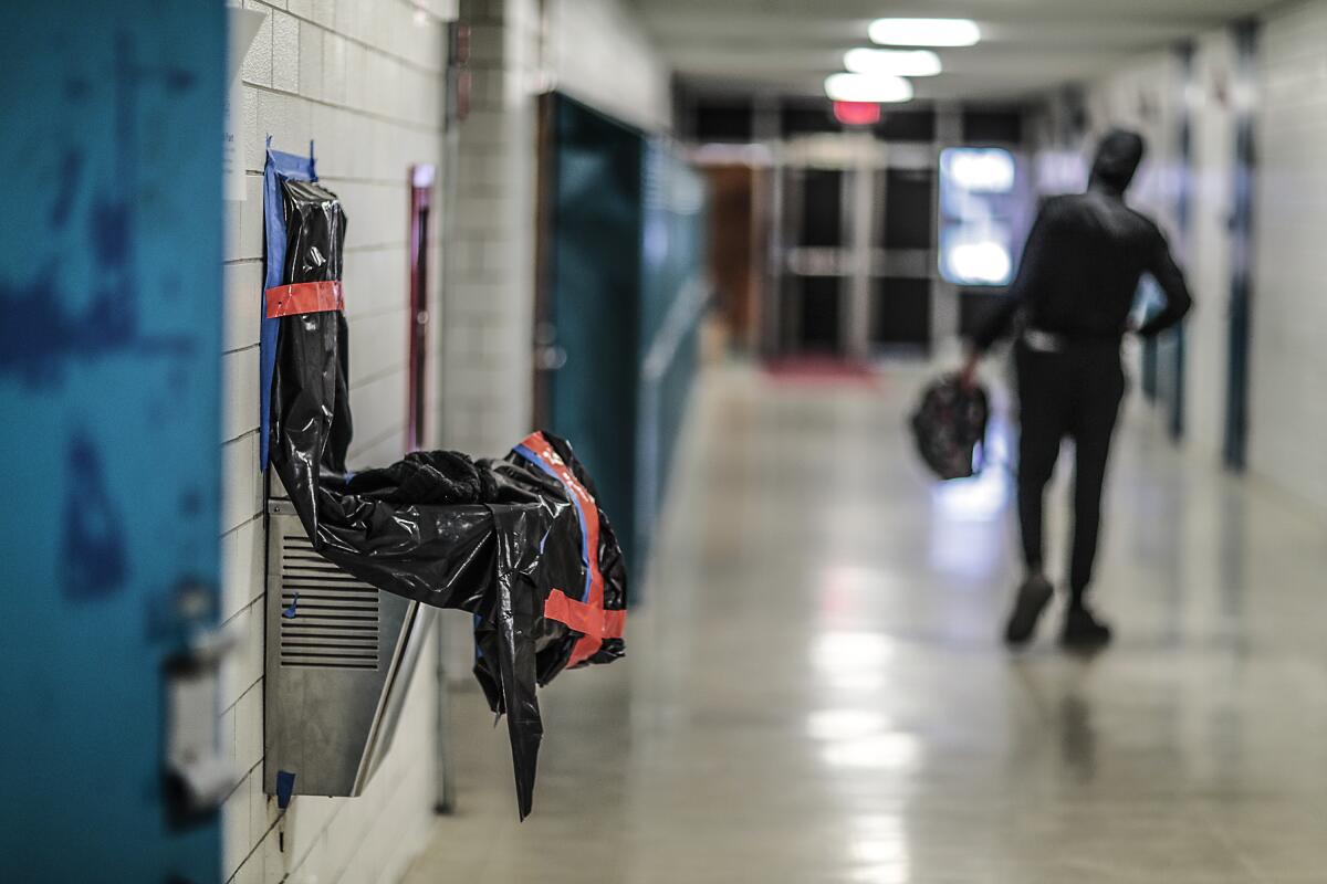 A drinking water fountain at a school is covered and taped off to prevent use.