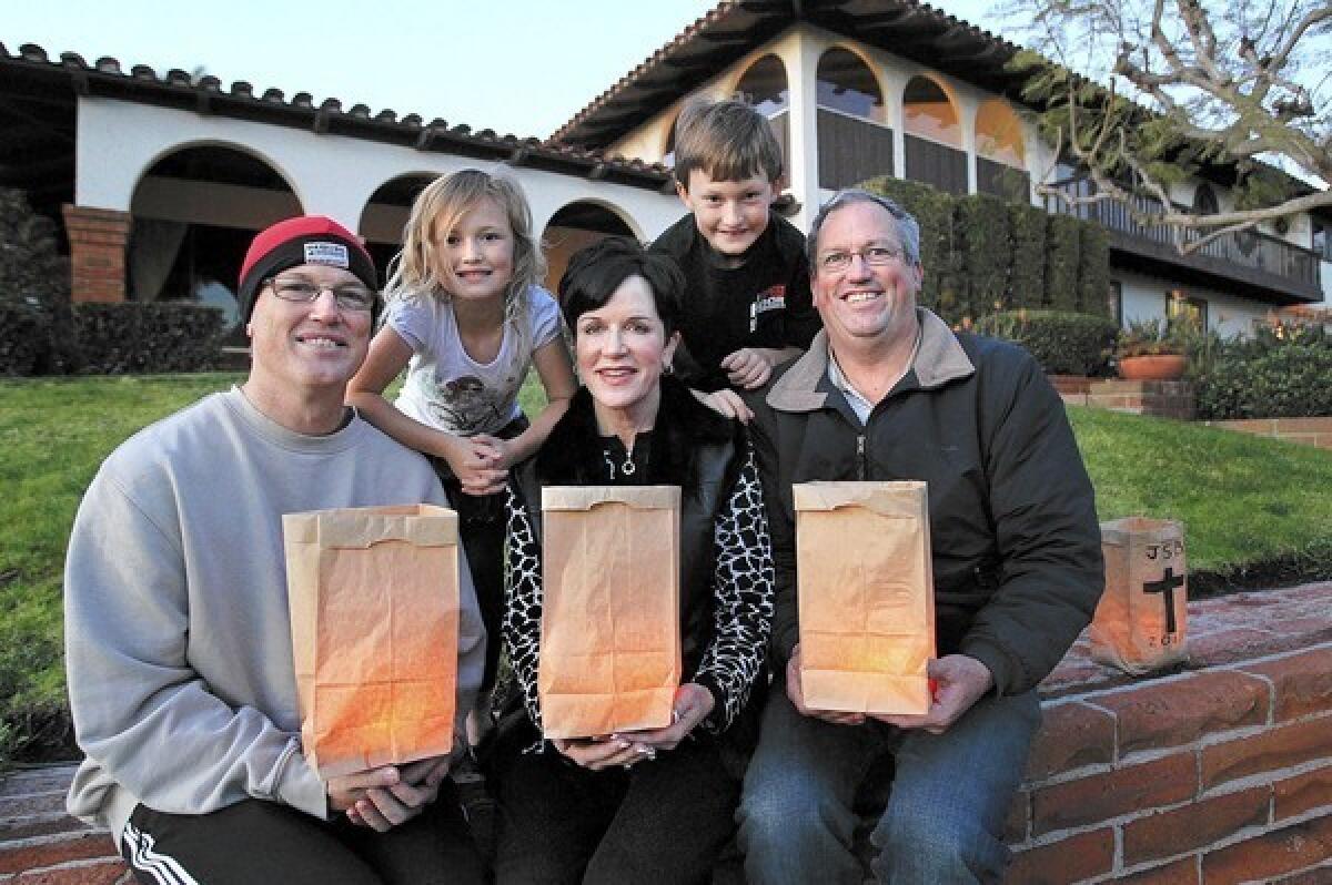 Siblings, from left, Lance Betson, Pam Barnett and Kevin Betson, and Lance's children Riley, 6, and Hayden, 8, gather at the family's former home in Newport Beach to light luminarias in honor of their recently deceased mother, Joan Sue Betson, who made a Christmas Eve tradition of the lighted candles.