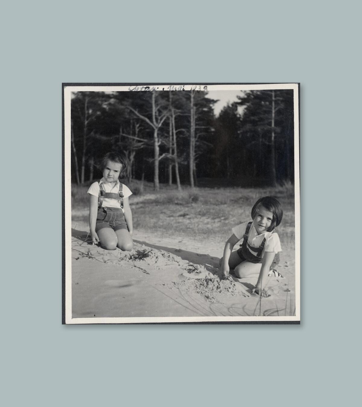A photograph of Betsy Kaplan with her twin sister as children playing in the sand.