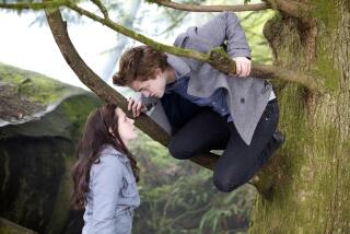 Kristen Stewart's Bella stares up at Robert Pattinson's Edward who is perched on a pair of branches