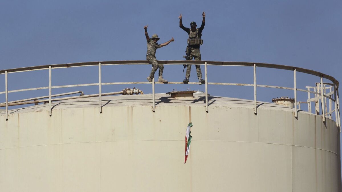 Iraqi government forces remove a Kurdish flag from the Bai Hasan oil field west of Kirkuk on Oct. 17.