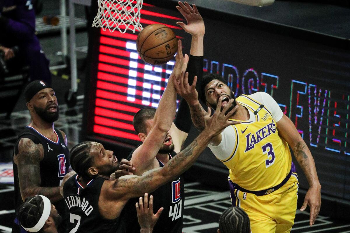 Lakers forward Anthony Davis attempts a reverse lay-up against the Clippers' Ivica Zubac and Kawhi Leonard.