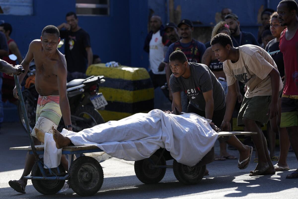 Residents use a cart to transport a body after a police operation that resulted in multiple deaths, in the Complexo do Alemao favela in Rio de Janeiro, Brazil, Thursday, July 21, 2022. Police said in a statement it was targeting a criminal group in Rio largest complex of favelas, or low-income communities, that stole vehicles, cargo and banks, as well as invaded nearby neighborhoods. (AP Photo/Silvia Izquierdo)
