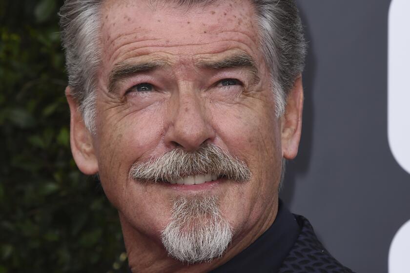 Pierce Brosnan with a mustache and goatee smiling