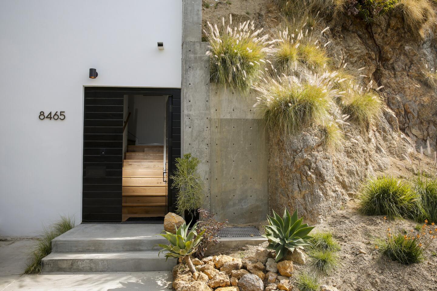 A custom all-wood front door greets visitors. Architect Ana Henton wanted the house to look as though it was “carved into the hillside.”