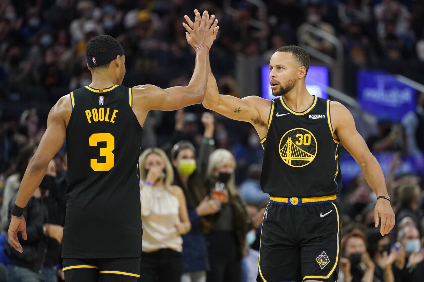 Stephen Curry (30), de los Warriors de Golden State, recibe la felicitación de su compañero Jordan Poole (3) tras anotar un triple en la primera mitad del juego de la NBA contra los Trail Blazers de Portland, en San Francisco, el 26 de noviembre de 2021. (AP Foto/Jeff Chiu)