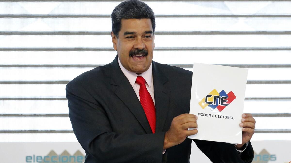 Venezuela's President Nicolas Maduro holds up the National Electoral Council certificate on May 22, 2018, declaring him the winner of the presidential election during a ceremony at CNE headquarters in Caracas, Venezuela.