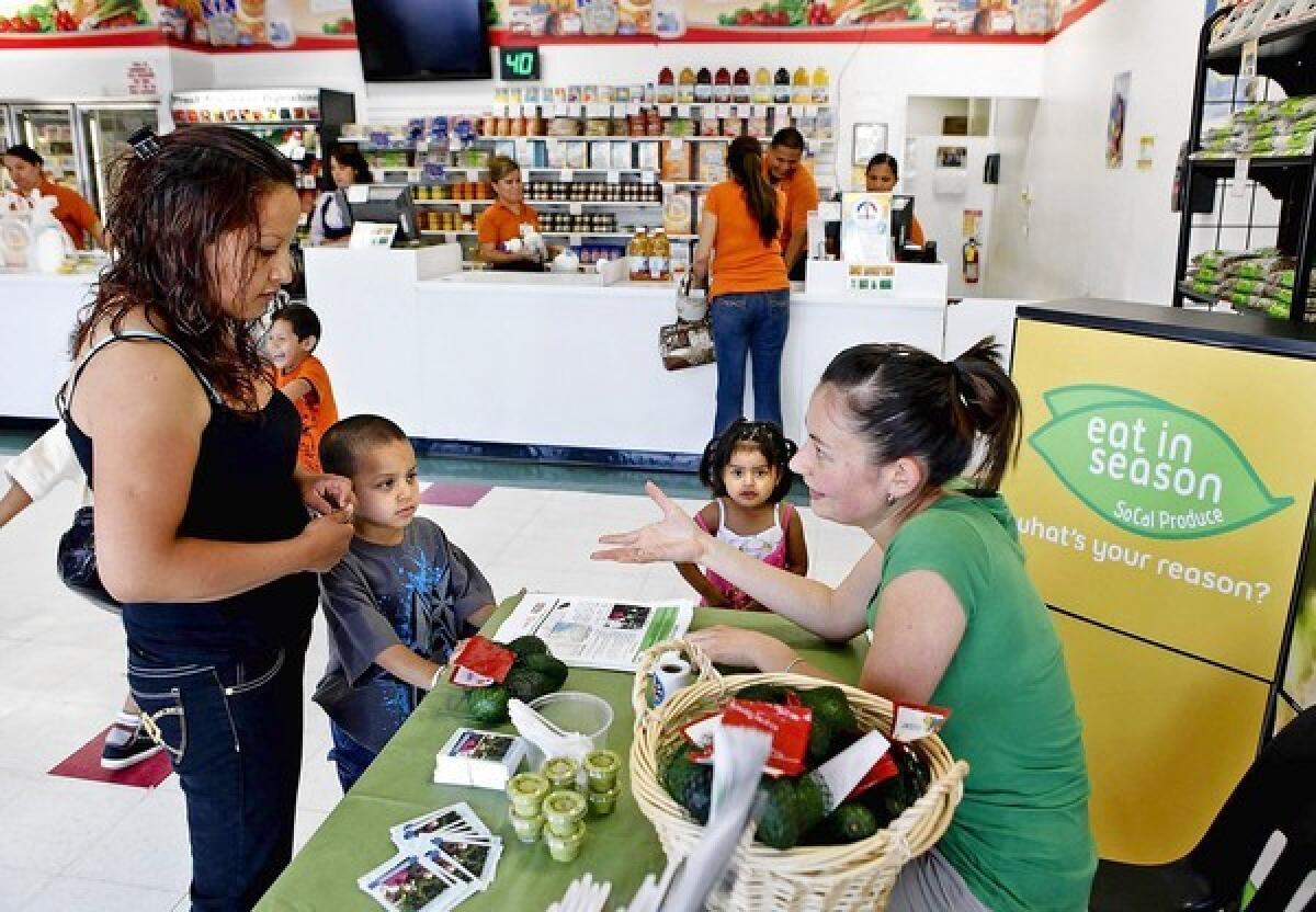 Yelena Zelster, with the Urban and Environmental Policy Institute, right, talks with Guadalupe Garcia and her kids Ricardo, 5, and Guadalupe, 2, as they give out a bag of avocados at Prime Time Nutrition as part of the farm to WIC program.