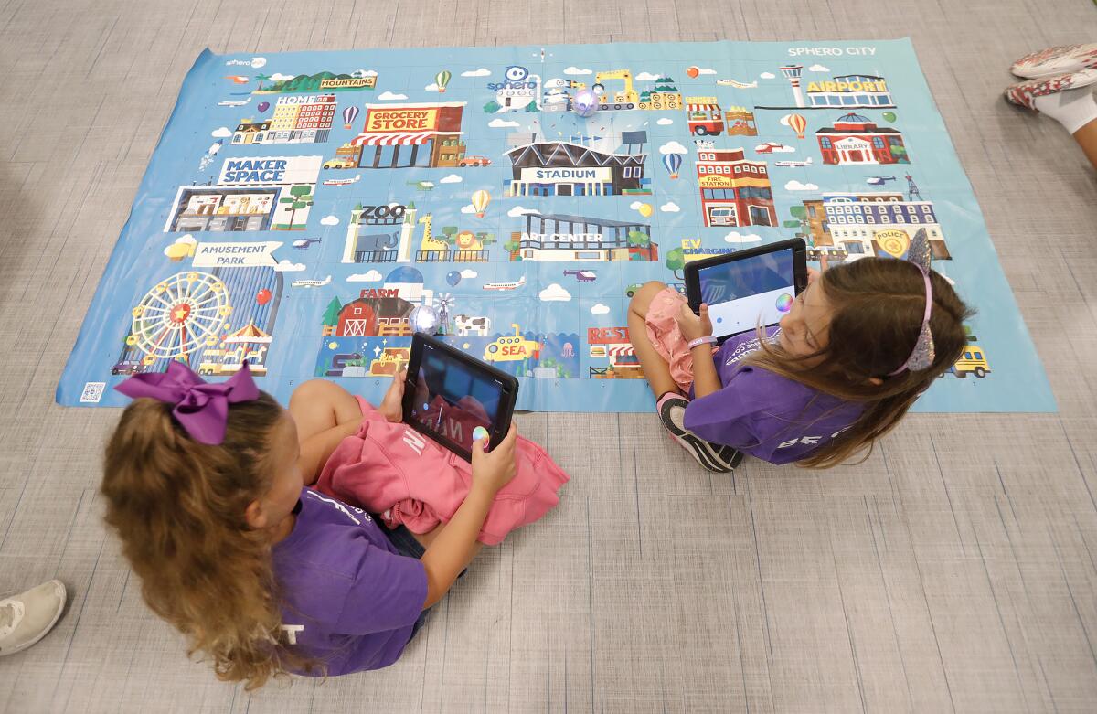 Ottavia Martinez and Olivia Martinez, from left, use an iPad to play a floor game.