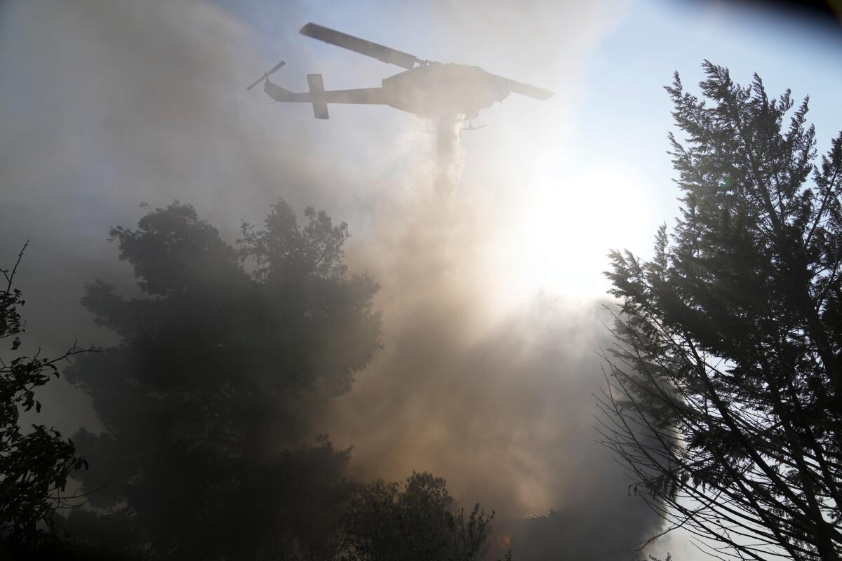 A helicopter drops water over a burning house in Vilia area, northwest of Athens, Greece.