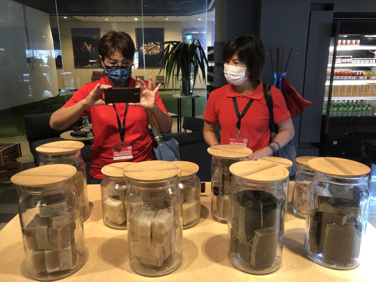 Rugayah Noordin, left, and Fiona Tay inspect jars of soap to ensure they can't be opened by customers per COVID rules