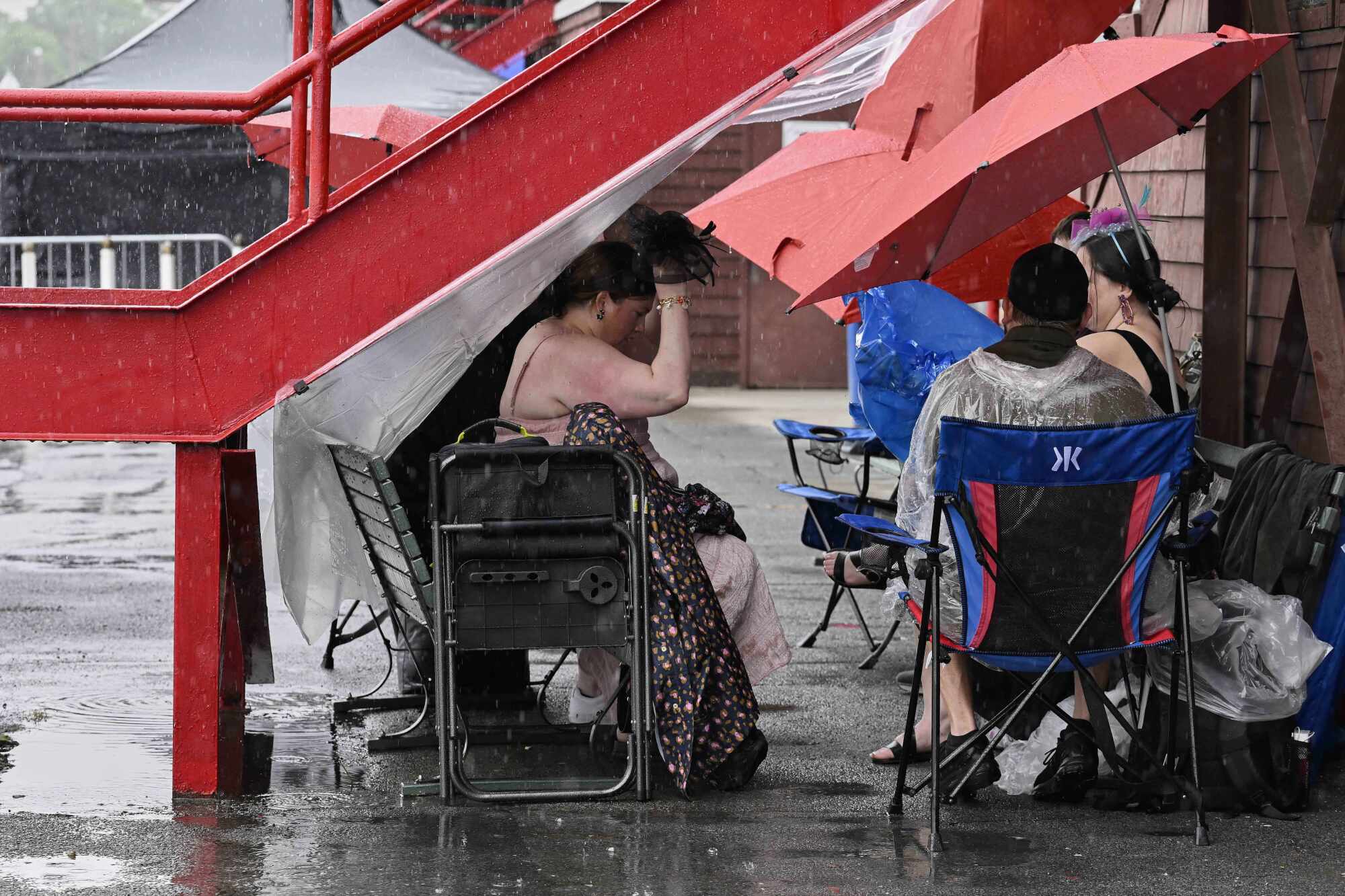 Horse racing fans take shelter from the rain under a stair case at Saratoga Race Course on Saturday.