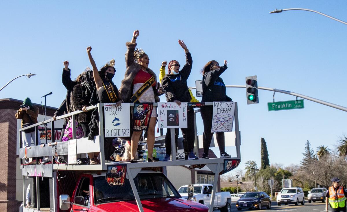 Participants cheer while riding atop a flatbed truck during a car caravan honoring Martin Luther King in Sacramento.