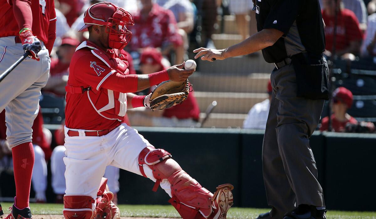 Angels catcher Carlos Perez has a baseball examined by home plate umpire Kerwin Danley during the first inning of a spring training baseball game against the Cincinnati Reds on March 14 in Tempe, Ariz.