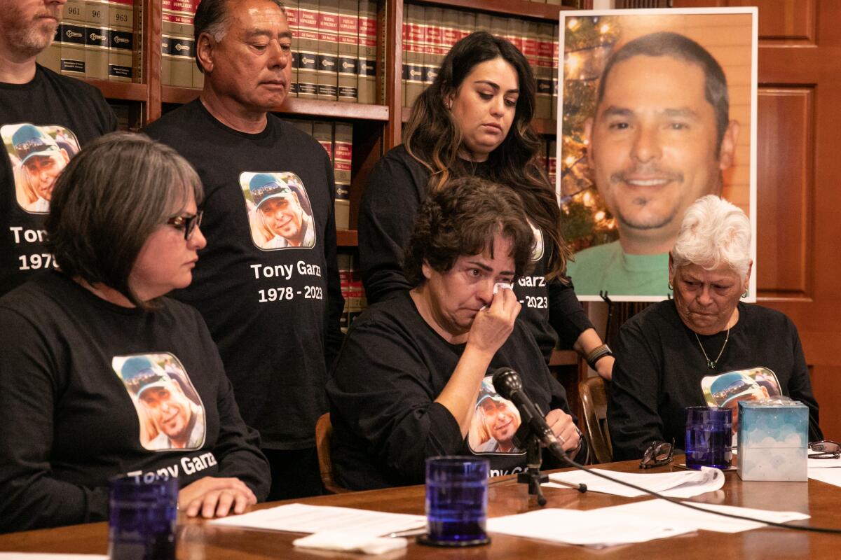 A woman wipes away tears as other family members of Tony Garza look on at a news conference.