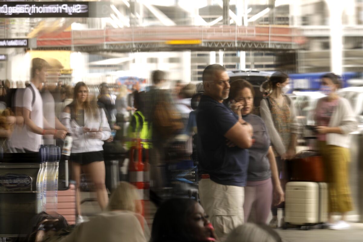 Travelers, caught in a reflection, begin their Memorial Day holiday getaway at the Los Angeles International Airport.