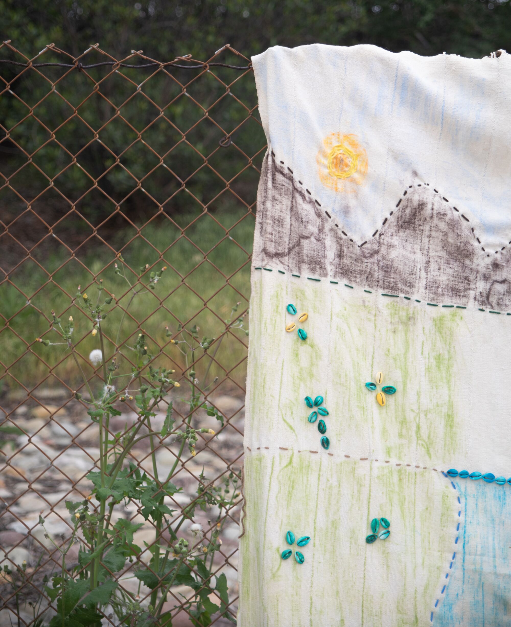 A detail of the textile showing the mountains and green pastures.