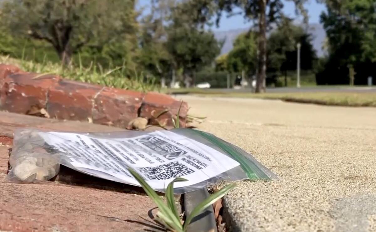 A plastic bag with a printed page inside sits along a walkway.