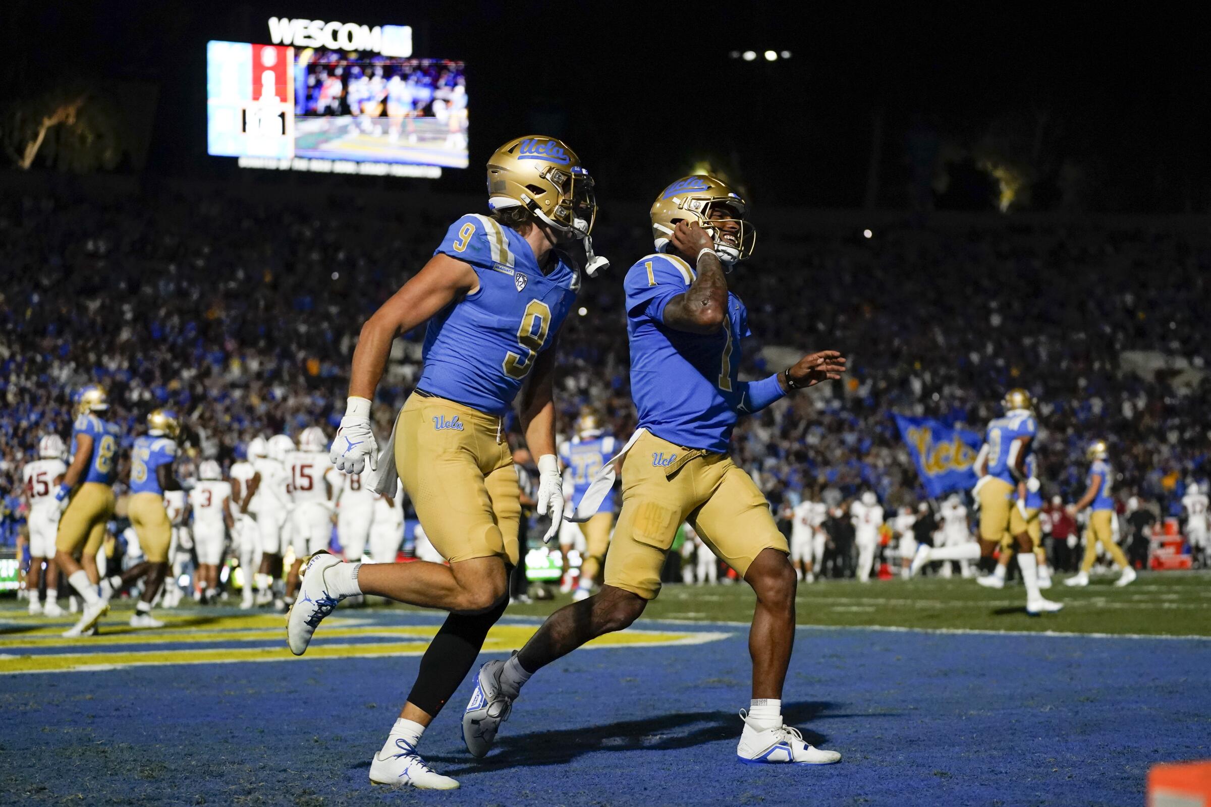 Jake Bobo and Dorian Thompson-Robinson run after scoring a touchdown for UCLA.