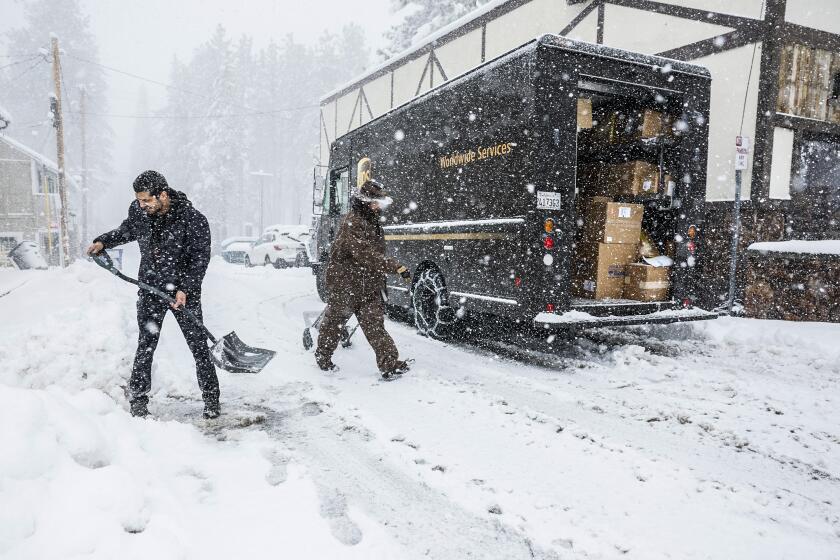 Big Bear, CA, Tuesday, February 6, 2024 - Saeed Fardin, part owner of Superhero Toys n More clears the sidewalk as a shipment of goods is delivered during a snowstorm in Big Bear. (Robert Gauthier/Los Angeles Times)