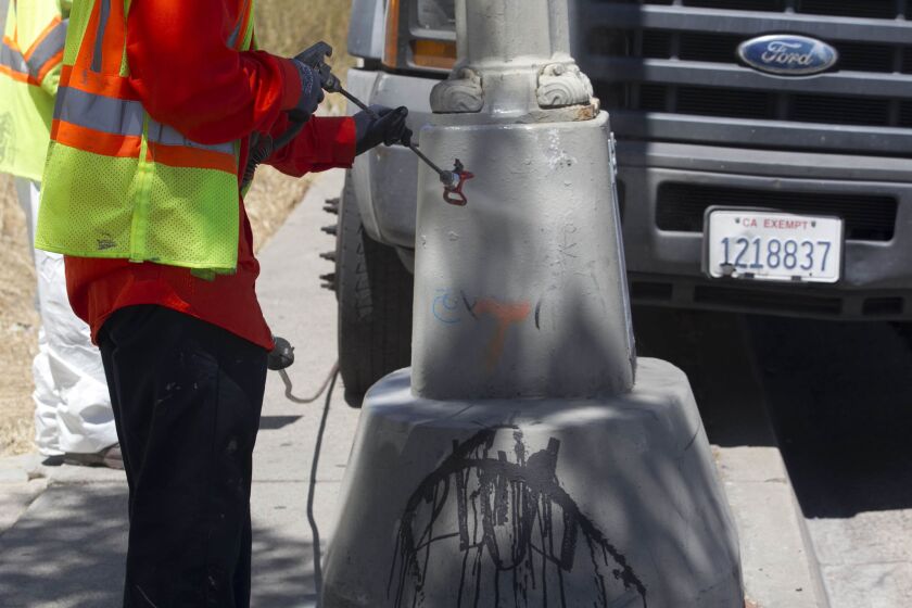 Graffiti on ta light pole base on the south side of University Ave. at 54th street gets spray pained over.