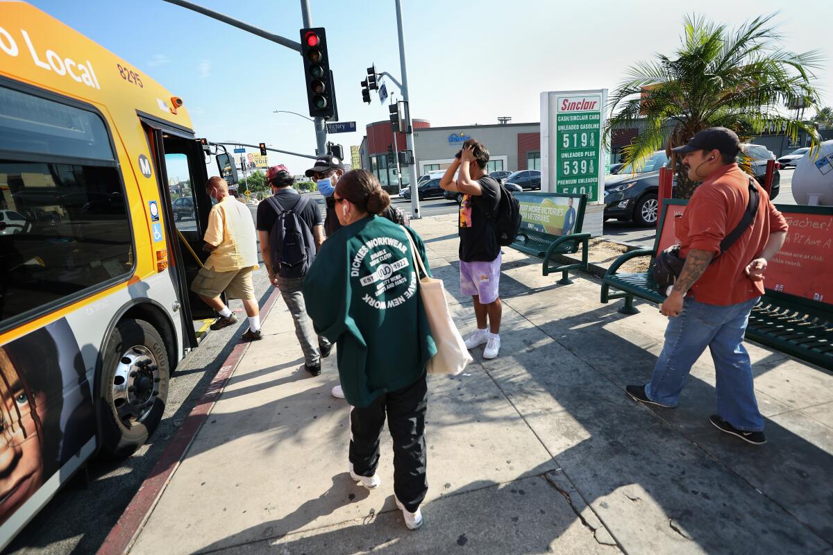 People board a Metro bus at a bus stop with no shade