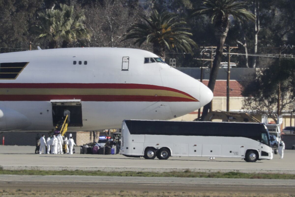 Workers in hazmat suits remove luggage and other cargo from the chartered jet that brought American evacuees from Wuhan, China, to March Air Reserve Base on Jan. 29. 