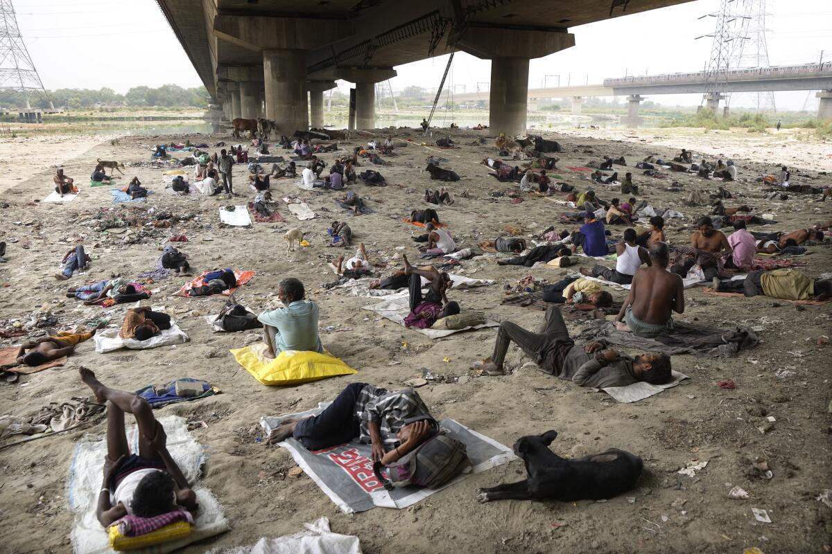 Indigentes duermen a la sombra de un puente en un día caluroso, el 20 de mayo de 2022, en Nueva Delhi.