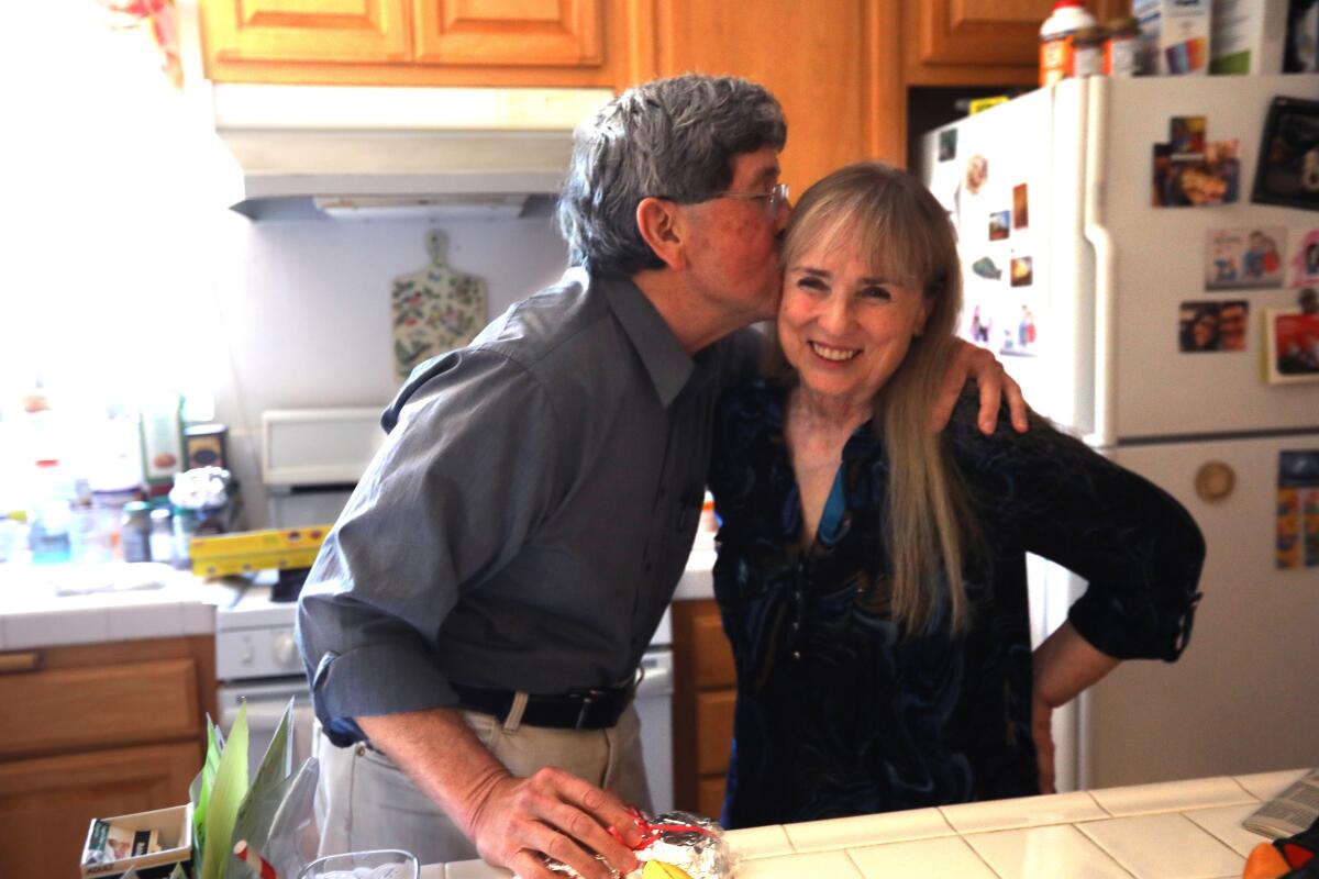 Dr. Gene Dorio kisses Robin Clough in the kitchen of their home.