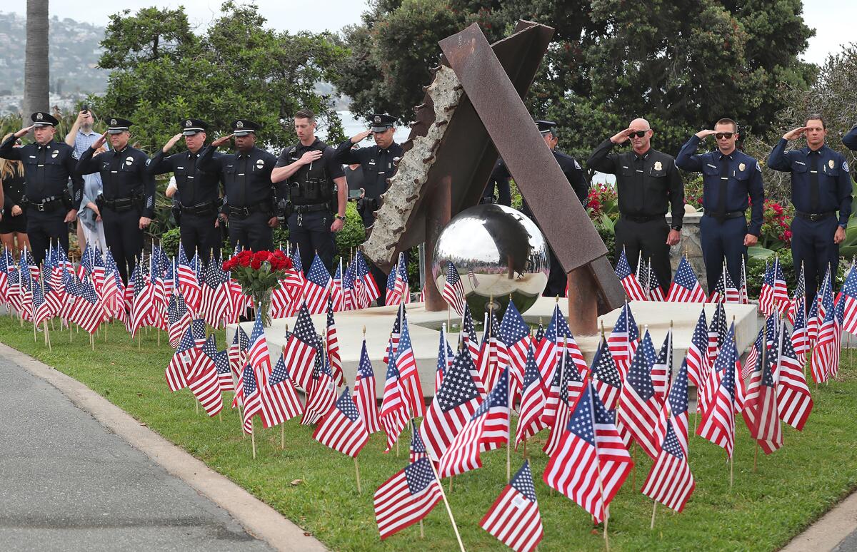 Laguna Beach fire and police personnel salute as they pay respects around the "Semper Memento" sculpture on Wednesday.