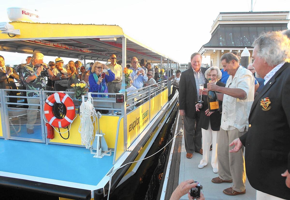 Guests crowd the deck as Newport Beach Councilman Keith Curry, former state legislator Marian Bergeson, Newport Mayor Ed Selich and Balboa Bay Club Chairman John Wortmann, from left, break open champagne as they unveil ExplorOcean's new educational vessel at the Balboa Bay Club dock on Wednesday. The boat will be used to take students on the water to learn about marine life.