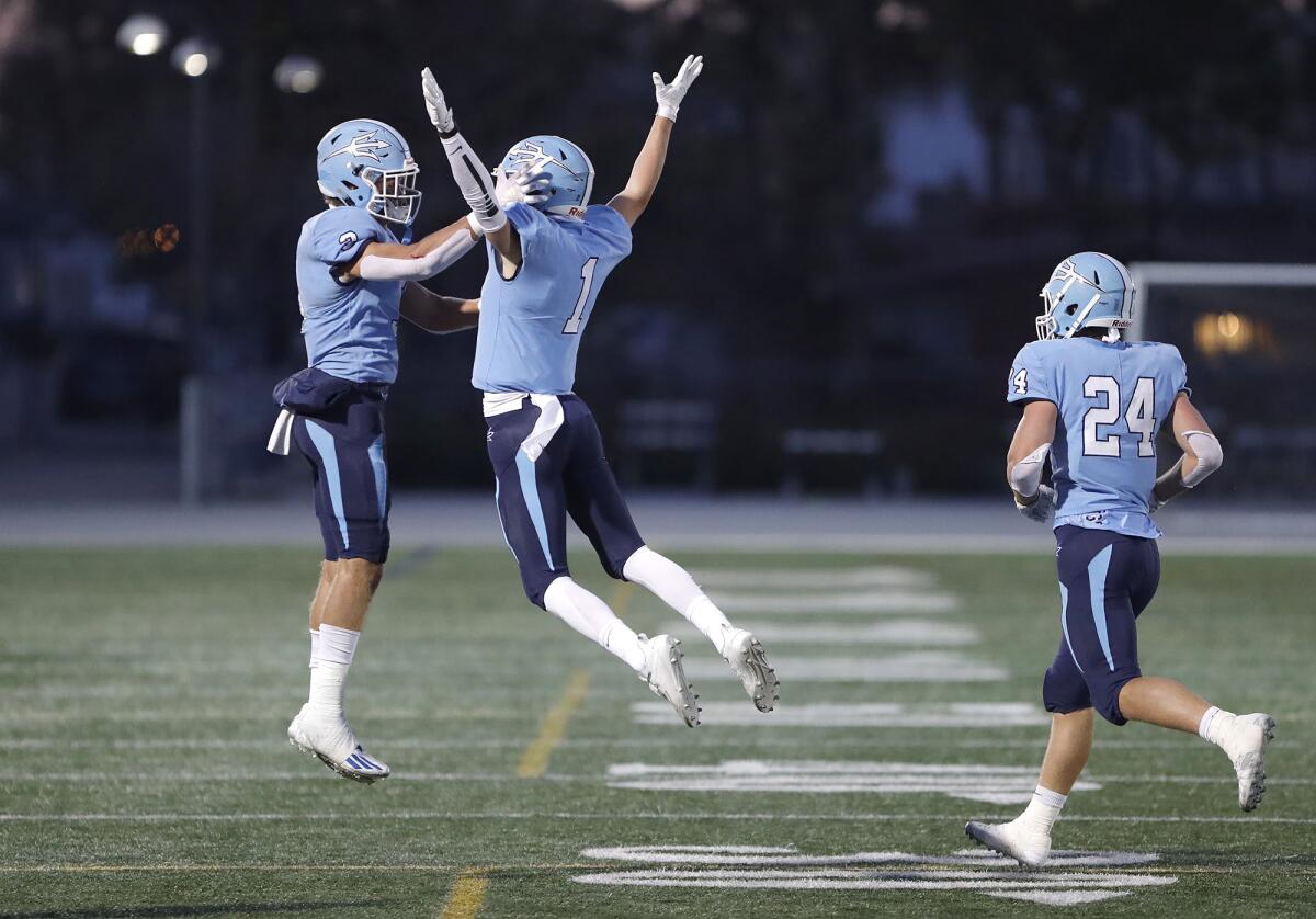 Corona del Mar's Max Lane (1) jumps into the arms of teammate Tommy Griffin (3) after scoring a touchdown on Friday.