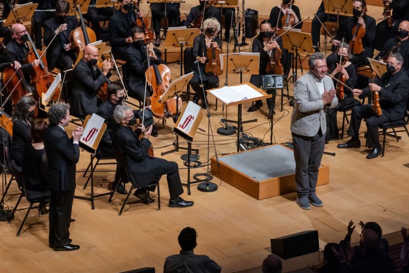 Composer Thomas Ades takes a bow with Gustavo Dudamel standing at the far left after The Los Angeles philharmonic performance of Dante at Walt Disney Concert Hall on April 28, 2022.
