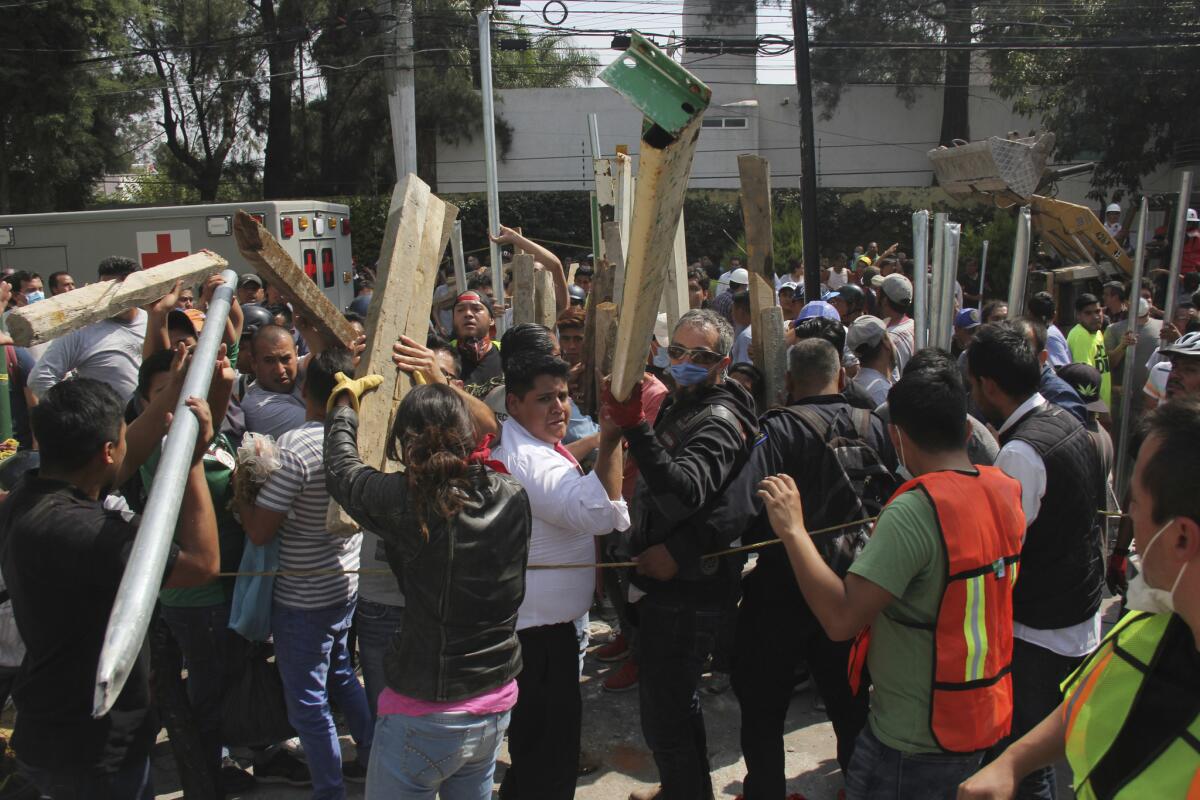 Volunteers bring pieces of wood to help prop up sections of the collapsed Enrique Rebsamen school, as rescue workers search for victims trapped inside. (Carlos Cisneros / Associated Press)