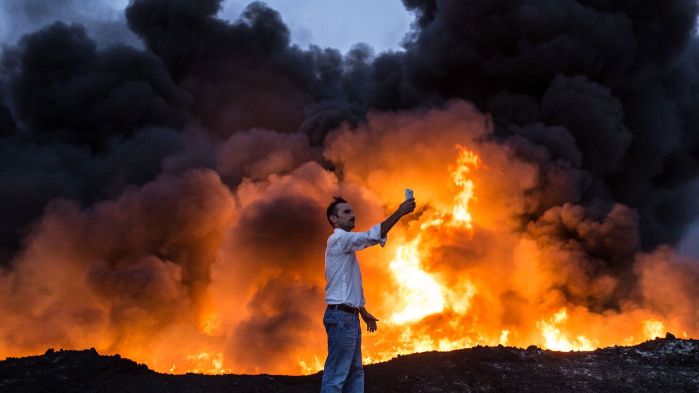 A man takes a selfie in front of a fire from oil that has been set ablaze in the Qayyarah area south of Mosul on Oct. 19, 2016, during an operation by Iraqi forces against Islamic State to retake Mosul.