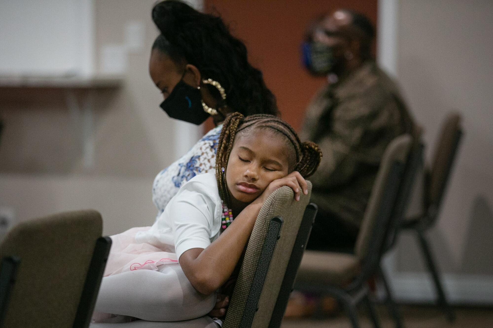 A young girls asleep in a chair at church.